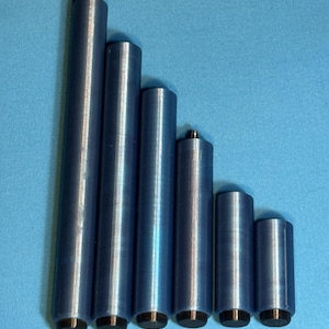 May include: Six blue cylindrical objects of varying heights, arranged in a descending order. Each cylinder has a black base. The objects are set against a light blue background.