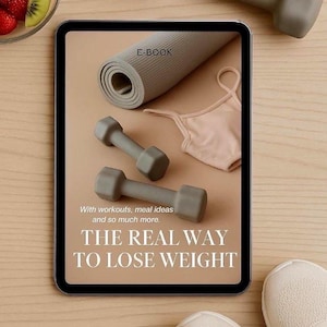Puede incluir: Imagen centrada en el fitness y el bienestar. Una tableta muestra un libro electrónico titulado "THE REAL WAY TO LOSE WEIGHT". Se ven pesas grises, una esterilla de yoga y un sujetador deportivo. También hay un cuenco de fruta y un par de zapatillas deportivas.