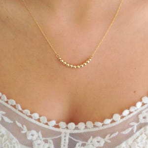 May include: A gold necklace with a delicate chain and a row of small, round beads.