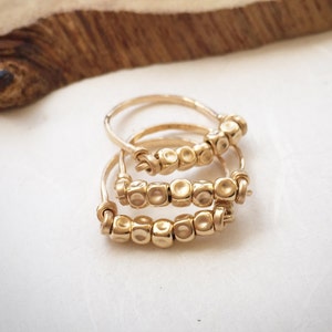 May include: Three gold rings with a row of small, round, textured beads. The rings are stacked on top of each other.