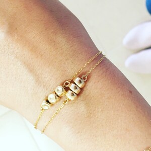 K&ouml;nnte beinhalten: Ein goldenes Kettenarmband mit einer Reihe kleiner, runder goldener Perlen.