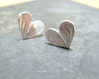 May include: Two silver heart-shaped earrings with a textured design.