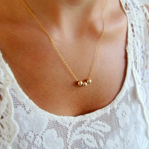 May include: A gold necklace with three small round beads.