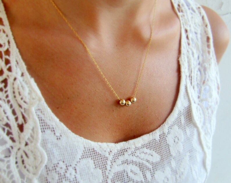 May include: A gold necklace with three small round beads.