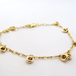 May include: A gold chain bracelet with multiple small, round charms hanging from it.