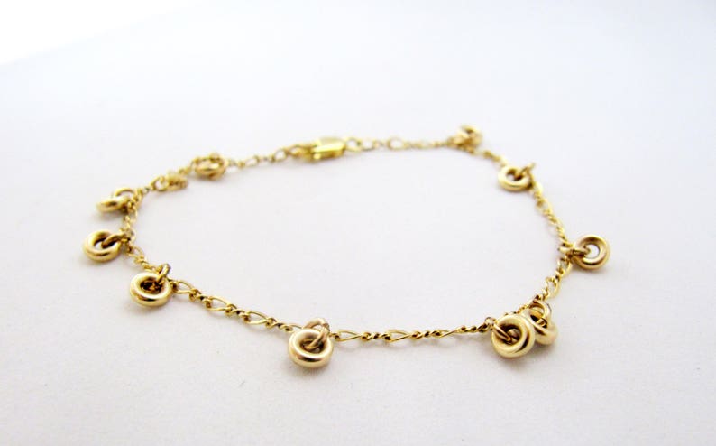 May include: A gold chain bracelet with multiple small, round charms hanging from it.