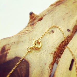 May include: A gold chain necklace with a lobster clasp closure. The chain is delicate and features a simple design.