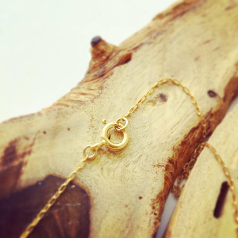 May include: A gold chain necklace with a lobster clasp closure. The chain is delicate and features a simple design.