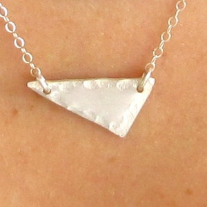 May include: A silver necklace with a hammered triangle pendant.