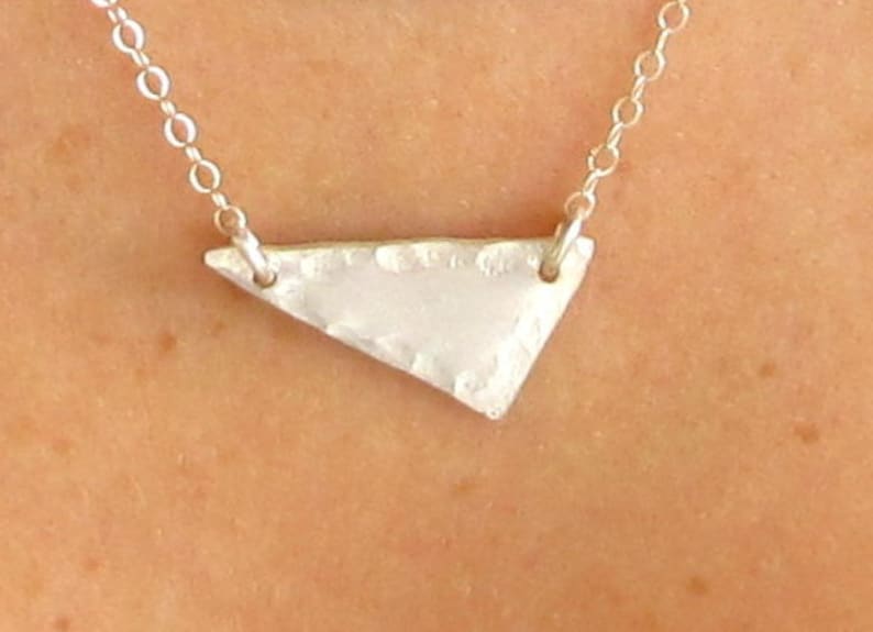 May include: A silver necklace with a hammered triangle pendant.