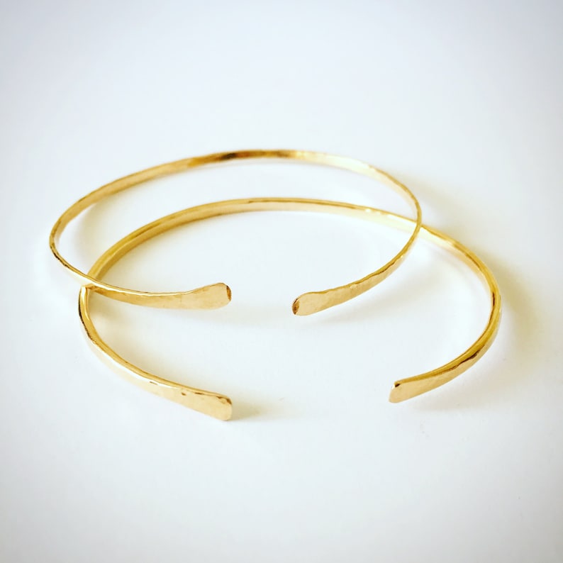 Puede incluir: Dos pulseras de brazalete de oro martilladas. Las pulseras son simples y elegantes, y ser&iacute;an un gran regalo.