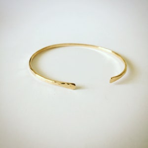 Puede incluir: Un brazalete de oro martillado con un dise&ntilde;o ligeramente abierto.
