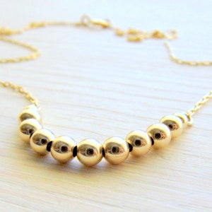 May include: A gold necklace with a chain and a row of round gold beads.