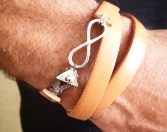 May include: A tan leather wrap bracelet with a silver infinity charm and a small silver triangle charm.