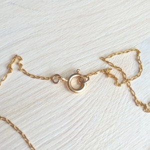 May include: A gold chain necklace with a lobster clasp closure.