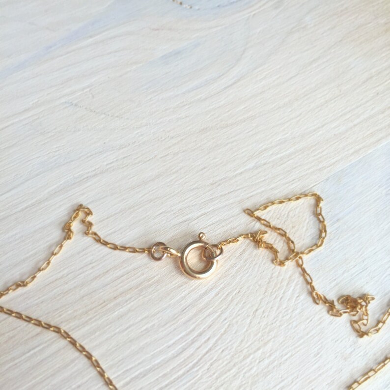 May include: A gold chain necklace with a lobster clasp closure.
