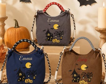 Puede incluir: Tres bolsas de tela en gris, azul marino y marrón, cada una con una escena de Halloween bordada con una casa encantada, una luna amarilla, murciélagos y calabazas. Las bolsas tienen nombres personalizados, Emma o Lucy, y asas de cuerda estampadas.