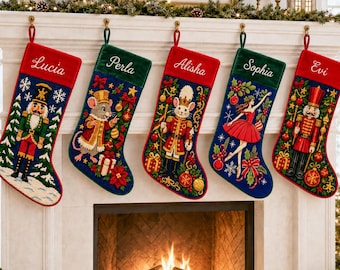 Puede incluir: Cinco calcetines de Navidad colgados en fila, cada uno con un diseño bordado único que incluye un cascanueces, un ratón, un soldado y una bailarina. Los calcetines tienen puños de terciopelo rojo o verde con los nombres Lucia, Perla, Alisha, Sophia y Evi bordados en letra blanca. Cada calcetín muestra motivos festivos como copos de nieve, adornos y follaje.