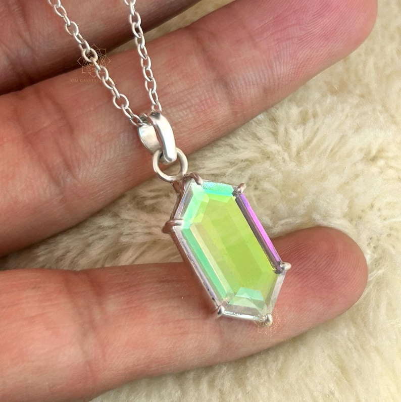 May include: A silver necklace featuring a rectangular, iridescent pendant with a faceted surface. The pendant displays shades of green, yellow, and purple. The chain is a delicate silver link design, and the pendant is held by a silver bail.