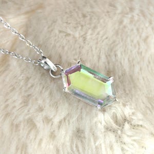 May include: A silver necklace with a rectangular pendant. The pendant has a clear, iridescent center with purple and green edges. The necklace chain is delicate and silver.