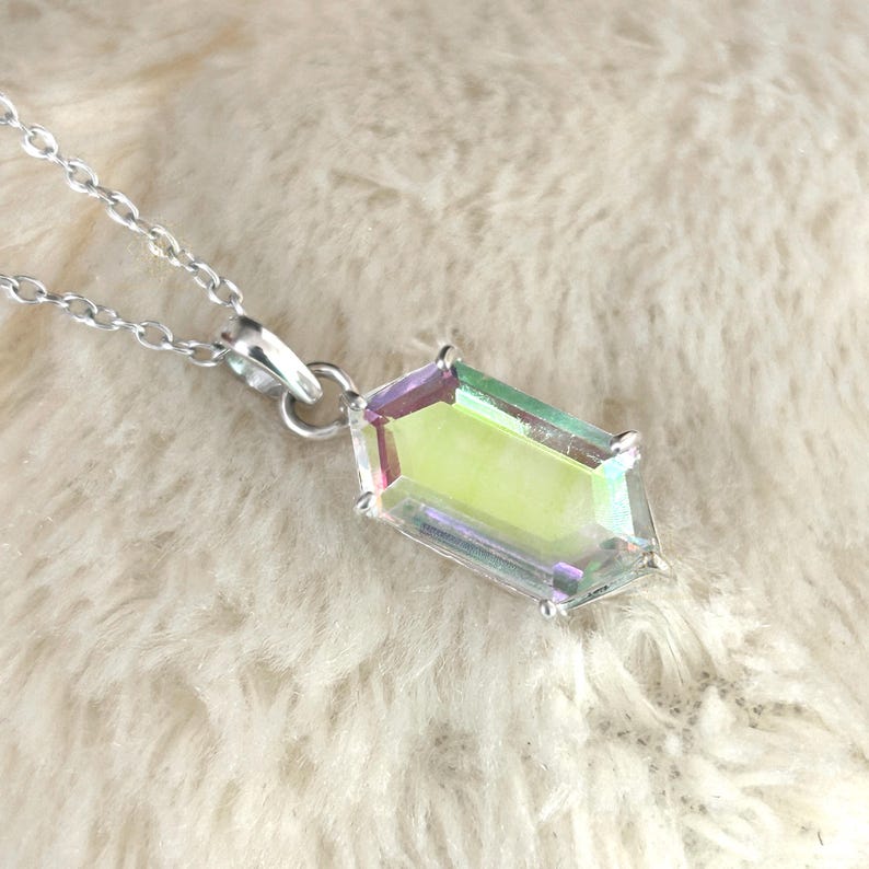 May include: A silver necklace with a rectangular pendant. The pendant has a clear, iridescent center with purple and green edges. The necklace chain is delicate and silver.