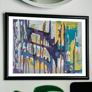 May include: Abstract art print in a black frame. The artwork features a mix of colors, including purple, yellow, teal, and silver, with a dripping paint effect. The painting is mounted on a white mat.