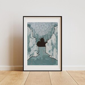 May include: Framed abstract art print featuring a dark silhouette of a building against a teal and white background. The artwork is enclosed in a black frame and rests on a wooden floor, leaning against a white wall. The art has a modern aesthetic.