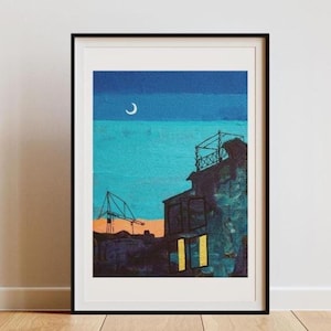 May include: Framed art print depicting a nighttime cityscape. The artwork features a crescent moon in a blue sky, with buildings and a crane in silhouette. The buildings have yellow illuminated windows. The art is framed in a black frame.
