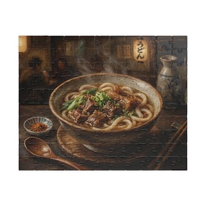 May include: A jigsaw puzzle featuring a detailed illustration of a bowl of udon noodles with beef, green onions, and broth. A wooden spoon, small dish of spices, and a sake bottle are also visible.