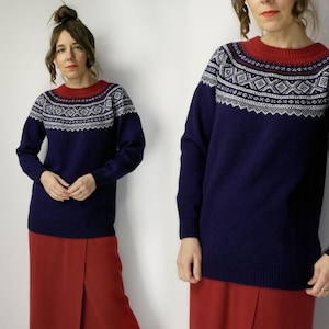 May include: A white ceramic mug with a black handle and the text "But First, Coffee" in a bold, black font. The mug is set against a blurred background, suggesting a cozy setting. The mug appears to be approximately 4 inches tall.