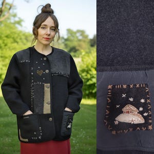 Könnte beinhalten: Schwarze Jacke mit Patchwork-Design, mit verschiedenen Texturen und Farben. Die Jacke hat einen runden Kragen, einen Knopfverschluss und zwei Vordertaschen. Dekorative Elemente sind ein Herz und gestickte Aufnäher mit Haus- und Sterndesign.