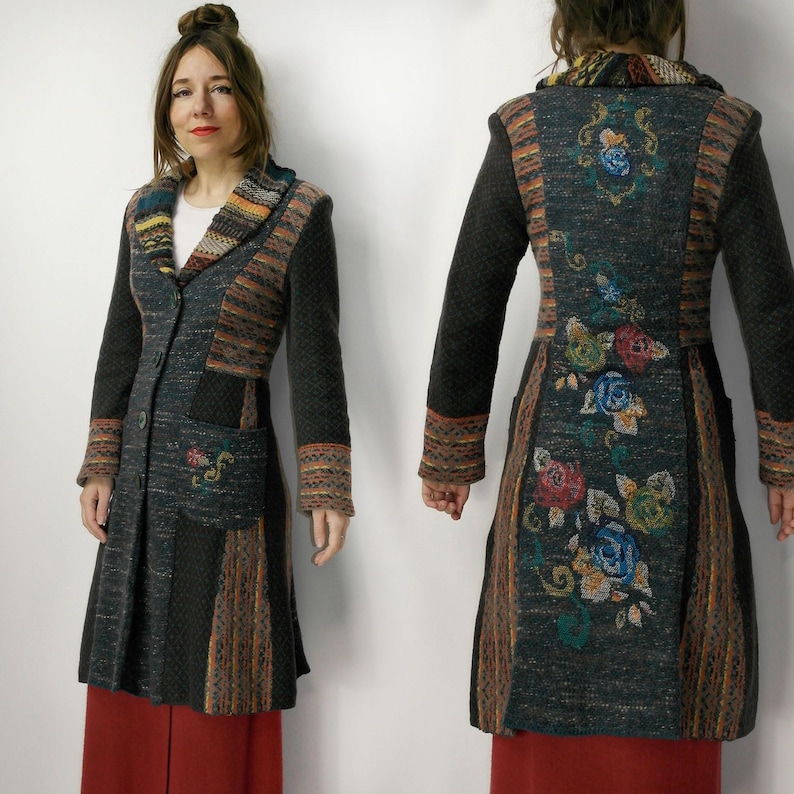 May include: A long, dark gray coat with colorful patterned accents and floral embroidery. The coat features a notched collar, button closure, and pockets. The back of the coat showcases a detailed floral design in various colors.