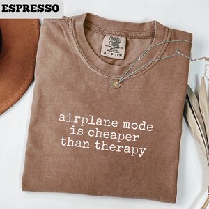 May include: A white ceramic mug with a black handle and the text "But First, Coffee" in a black, bold font. The mug is on a white surface. The mug is 4 inches tall.