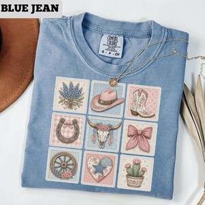 May include: Blue Comfort Colors t-shirt with a grid of nine square patches featuring Western-themed illustrations. Patches include a cowboy hat, boots, horseshoe, and floral designs. The text "BLUE JEAN" is at the top left.