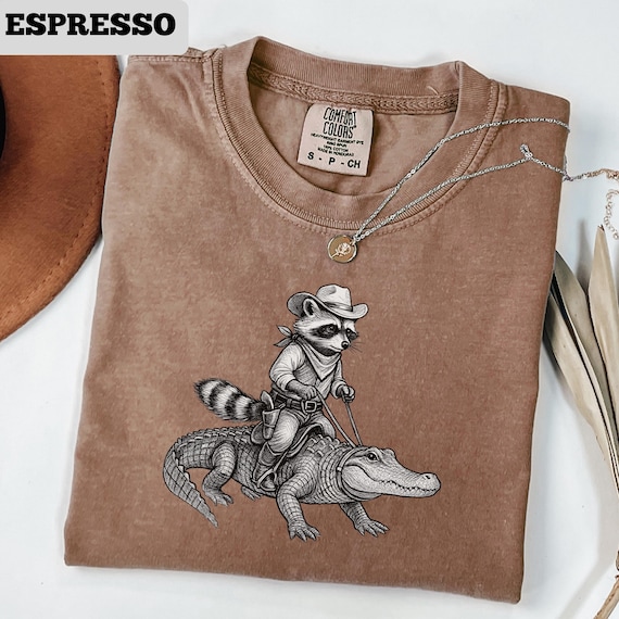 Vintage Cowboy Raccoon Riding Alligator T-Shirt, Western Animal Lover Tee, Vintage Wildlife Adventure Shirt, Funny Cartoon Ranch Tee