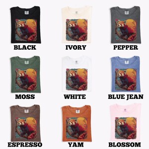 Puede incluir: Nueve camisetas de diferentes colores, cada una con un gr&aacute;fico de panda rojo. Los colores incluyen negro, marfil, pimienta, musgo, blanco, azul vaquero, espresso, &ntilde;ame y flor. El gr&aacute;fico muestra un panda rojo en una rama con una luna amarilla.