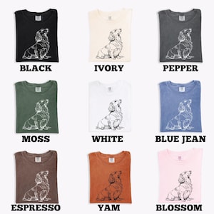 May include: Nine different colored t-shirts, each featuring a detailed line drawing of a dachshund. Colors include black, ivory, pepper, moss, white, blue jean, espresso, yam, and blossom. Each shirt has the color name printed below.