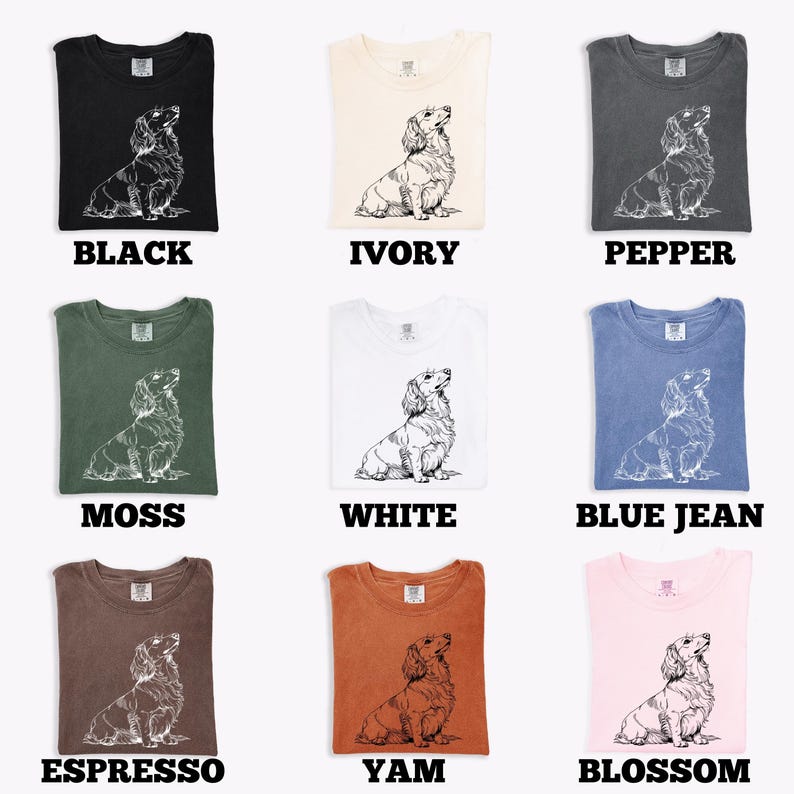 May include: Nine different colored t-shirts, each featuring a detailed line drawing of a dachshund. Colors include black, ivory, pepper, moss, white, blue jean, espresso, yam, and blossom. Each shirt has the color name printed below.