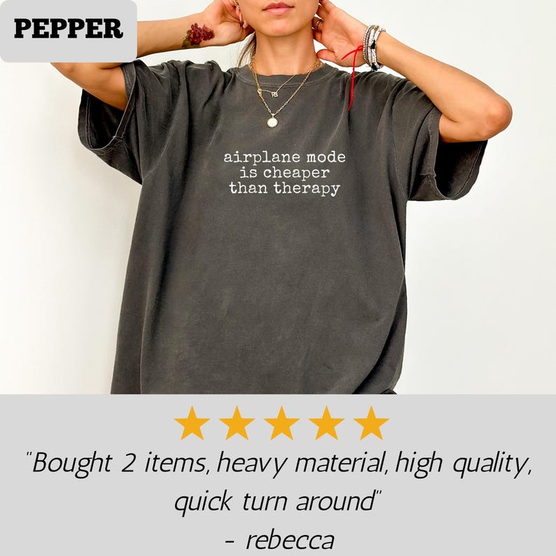 May include: Dark gray t-shirt with the text "airplane mode is cheaper than therapy" in white. The shirt is a relaxed fit and has short sleeves. The brand name "PEPPER" is in a white box in the upper left corner.