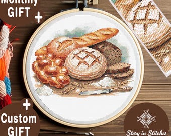 Könnte beinhalten: Ein Kreuzstich-Stickrahmen mit einem detaillierten Bild verschiedener Brotsorten, darunter ein Baguette, runde Laibe und Brötchen. Der Text "Monthly GIFT + Custom GIFT" ist sichtbar. Das Design befindet sich vor einem Holzgrund.