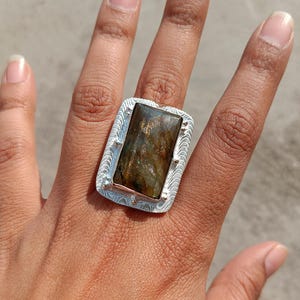 Anillo rectangular de labradorita hecho a mano en plata de ley 925, con marco texturizado y piedras preciosas.