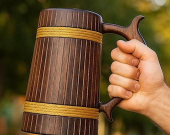 Könnte beinhalten: Ein dunkelbrauner Bierkrug aus Holz mit vertikalem Lamellendesign und zwei horizontalen Bändern aus gelbem Seil. Der Krug verfügt über einen geschwungenen Holzgriff an der Seite, der durchgehend eine natürliche Holzmaserung aufweist.