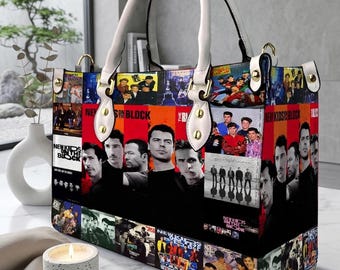 May include: A white-handled tote bag featuring a collage of images and text related to the band New Kids on the Block. The bag has a rectangular shape with a white handle and gold-colored hardware.
