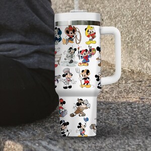 May include: White insulated tumbler featuring a repeating pattern of Mickey Mouse in various costumes. The tumbler has a white handle, lid, and straw. The design includes Mickey as a cowboy, artist, chef, and more.