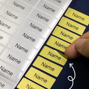 May include: Close-up of rectangular labels printed with the word "Name". Some labels are white, others are yellow. The text "Custom name" is written in a script font at the bottom of the image.