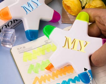Può includere: Evidenziatori a forma di stella con punte multicolore. Ogni penna ha la scritta "MY". L'immagine mostra anche un quaderno con linee evidenziate in vari colori e le parole "Custom text".