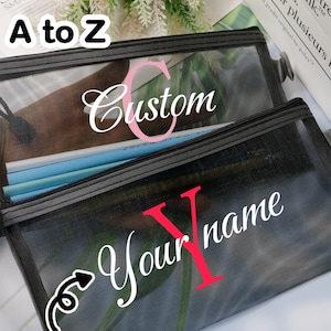 Könnte beinhalten: Zwei schwarze Federmäppchen aus Mesh mit Reißverschlüssen. Ein Etui trägt das Wort "Custom" mit einem rosa "C" und das andere "Your name" mit einem roten "Y". Der Text "CUSTOM A to Z" und "CUSTOM TEXT" sind ebenfalls sichtbar.
