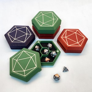 May include: Hexagonal dice boxes in green, red, and purple with white geometric designs. One box is open, revealing dice in various colours. The boxes are designed to hold and display dice.