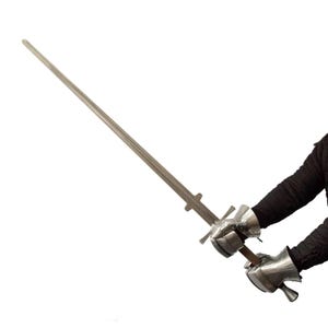 May include: A long, straight steel sword with a crossguard and a pommel, held by two hands encased in articulated metal gauntlets. The blade is double-edged and tapers to a point, while the hilt features a simple cross-shaped guard design.