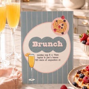 May include: A vertical rectangular brunch invitation card with a blue and white striped background. The card features a large pink circle containing a waffle with berries, a glass of orange juice, and the text: Brunch, sunday sep 8 @ 11am, taylor & jim's house, 123 main st anywehre st.